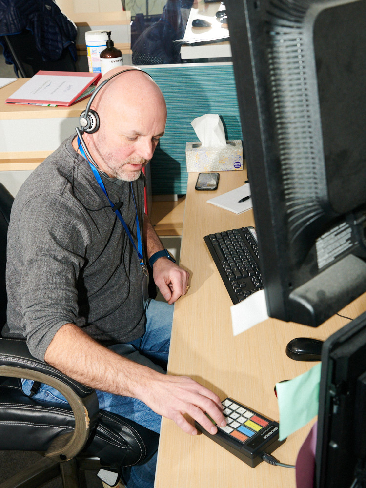 A 911 dispatcher takes a call at his desk