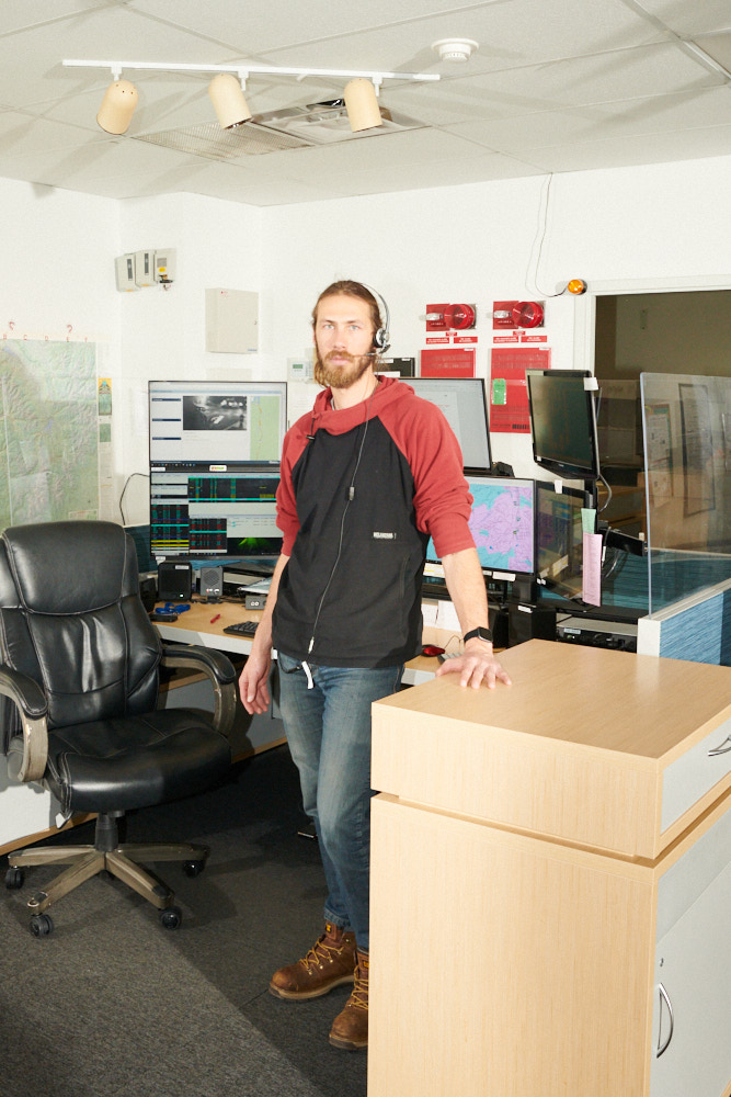 A 911 dispatcher stands for a portrait at his desk
