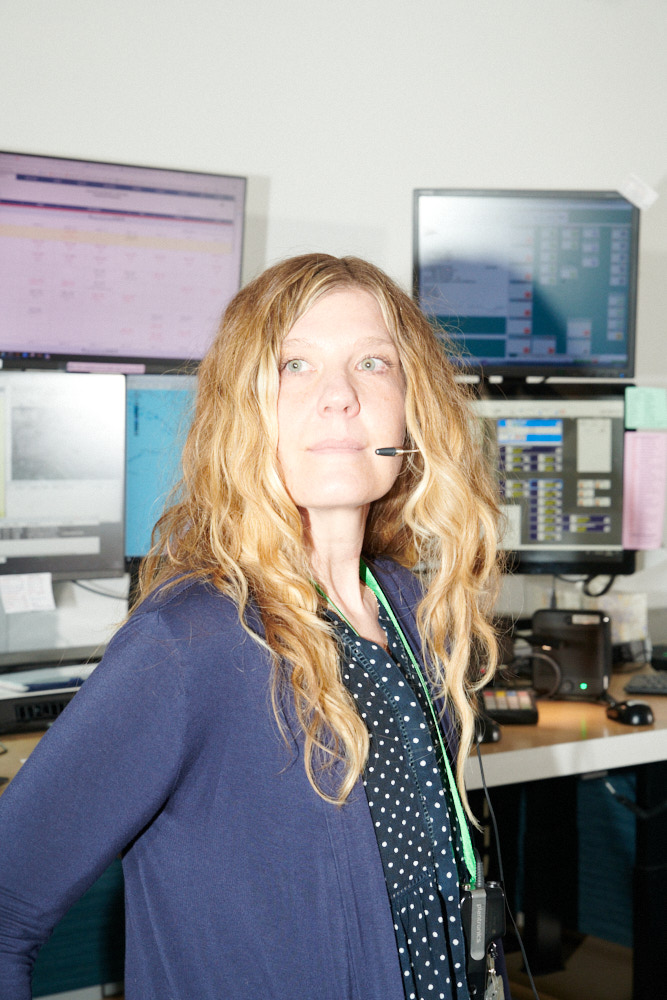 A 911 dispatcher poses for a portrait at her workstation