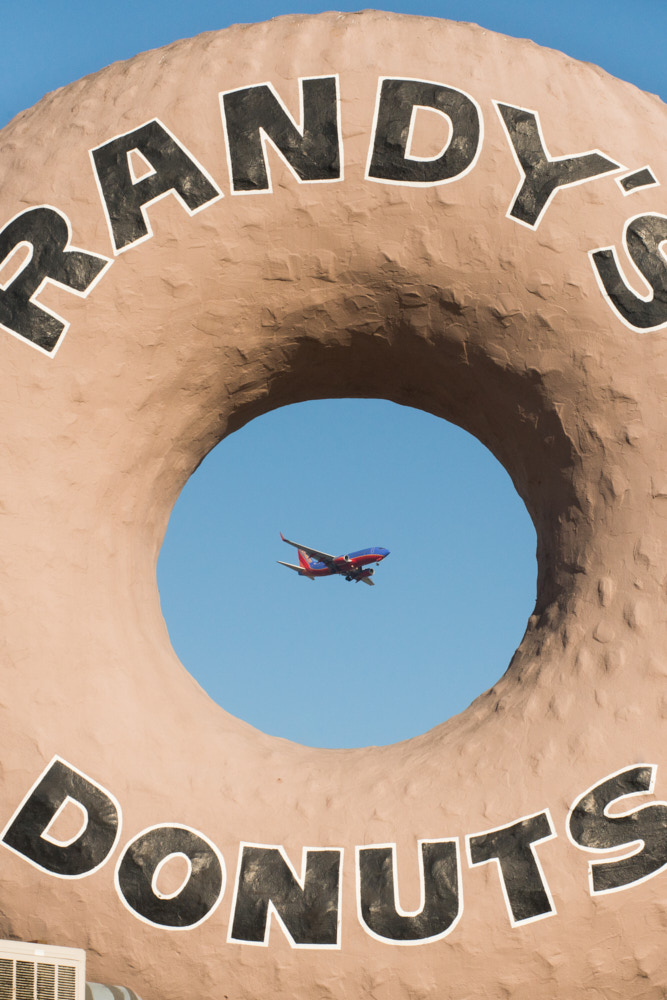 An airplane flying past Randy's Donuts