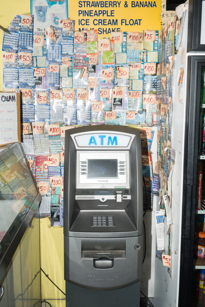 An ATM at a donut shop with winning lottery tickets on the wall behind it