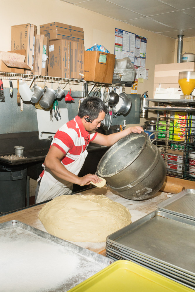A baker preparing donuts with a large ball of dough