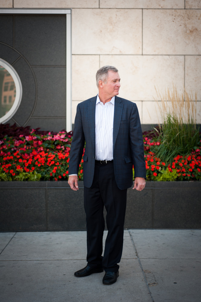 A businessman poses for a portrait in front of garden boxes