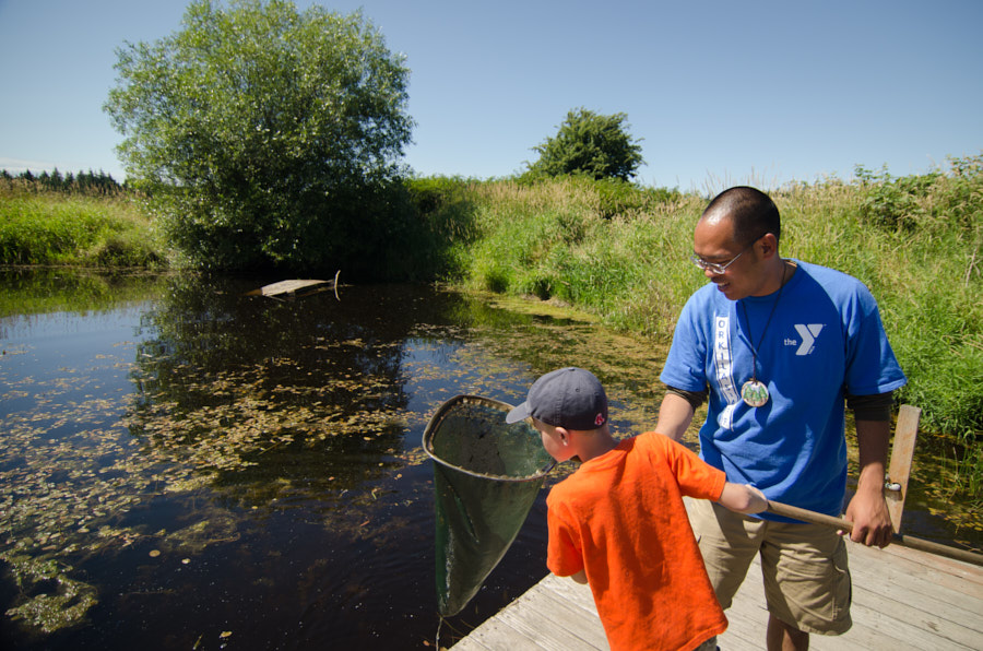 A counselor and camper look for fish in a net at a lake