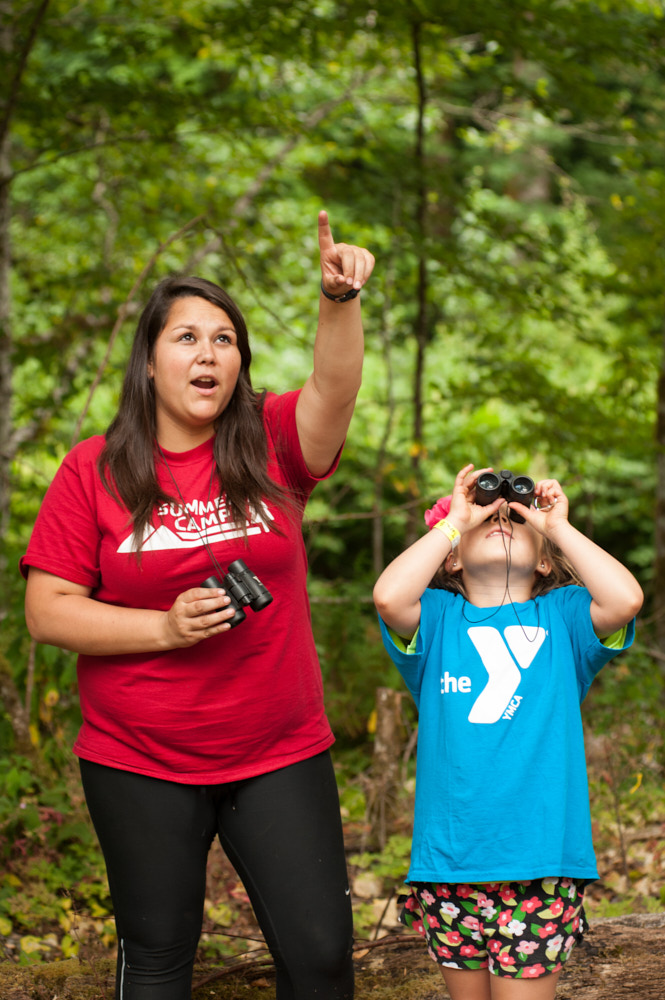 A counselor uses binoculars with a camper