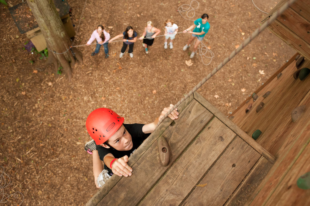 A camper wearing a helmet climbs a challenge wall