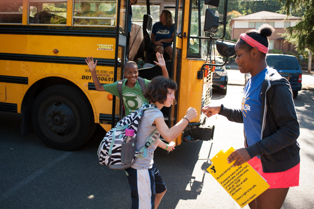 A counselor fist bumps a camper exiting a school bus