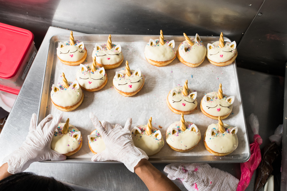 Gloved hands preparing decorated unicorn donuts