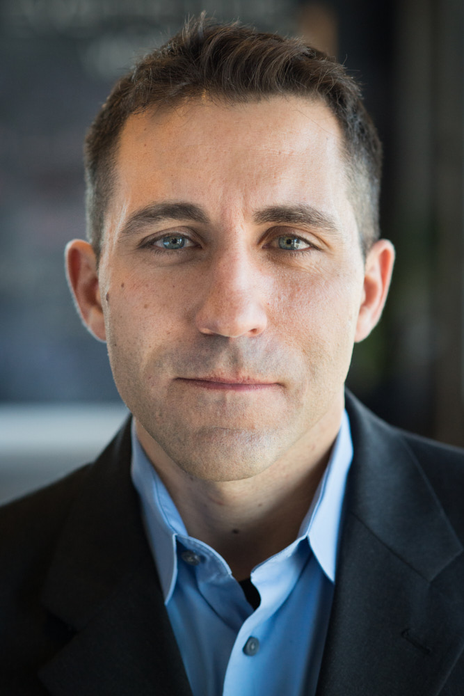 A businessman poses for a headshot portrait in his office