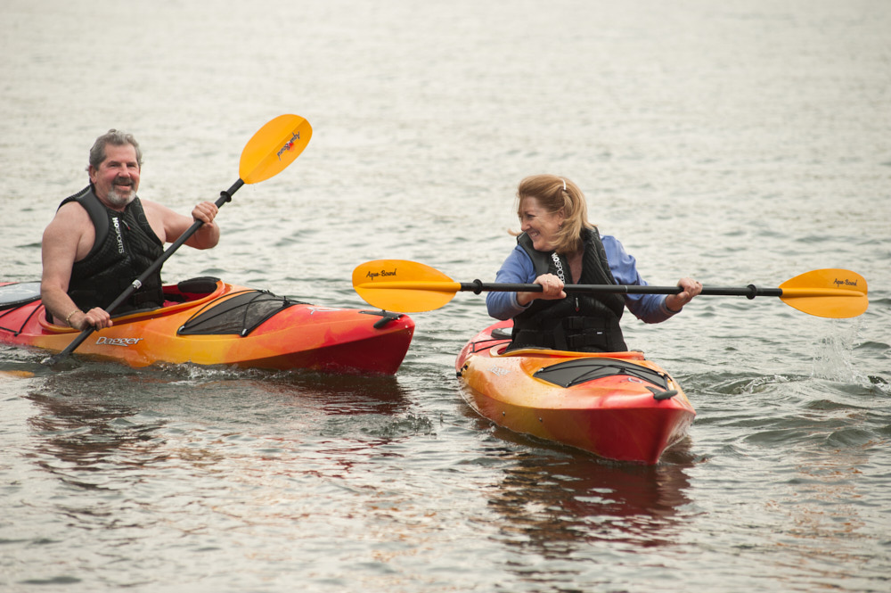 An elderly couple smiling and kayaking