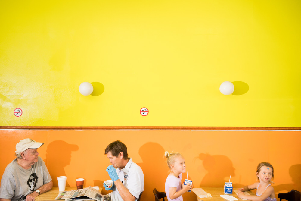 Four people sitting in a brightly colored donut shop.