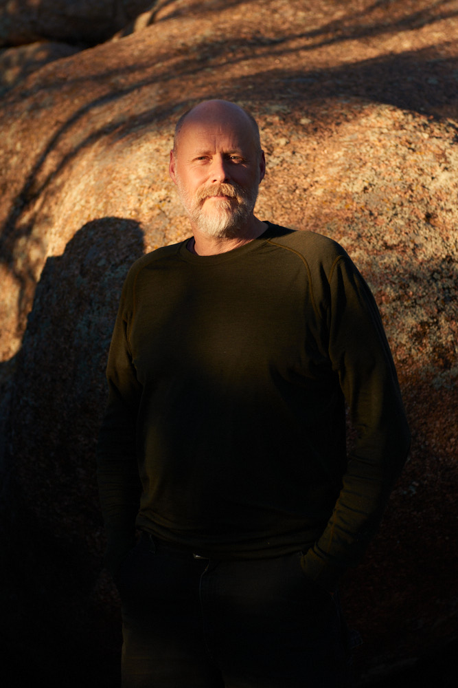 A portrait of Jason Shogren at sunset in front of rocks