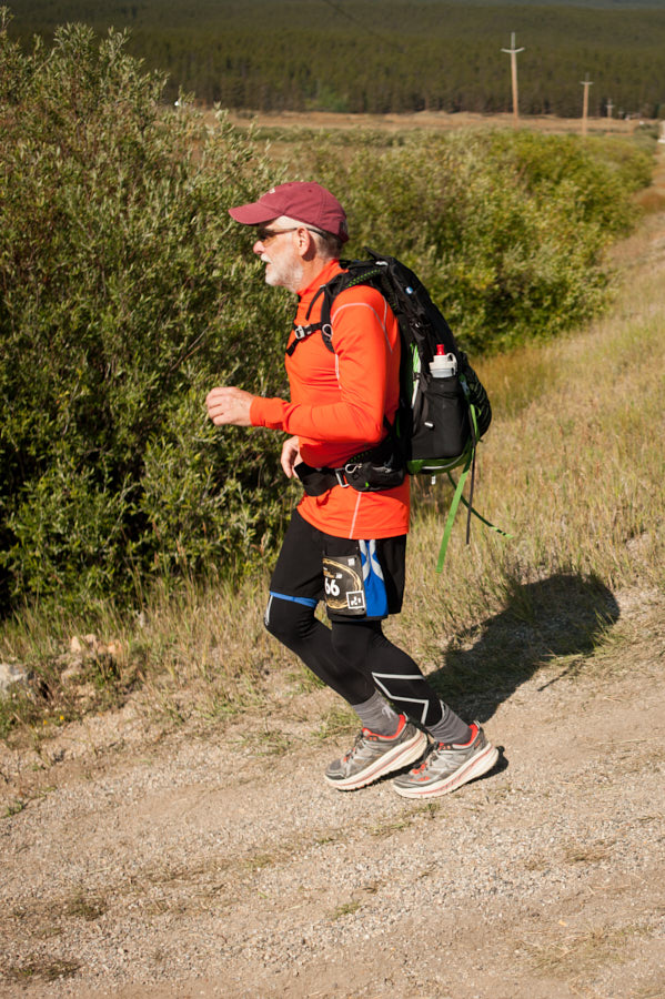 An elderly man running with a backpack