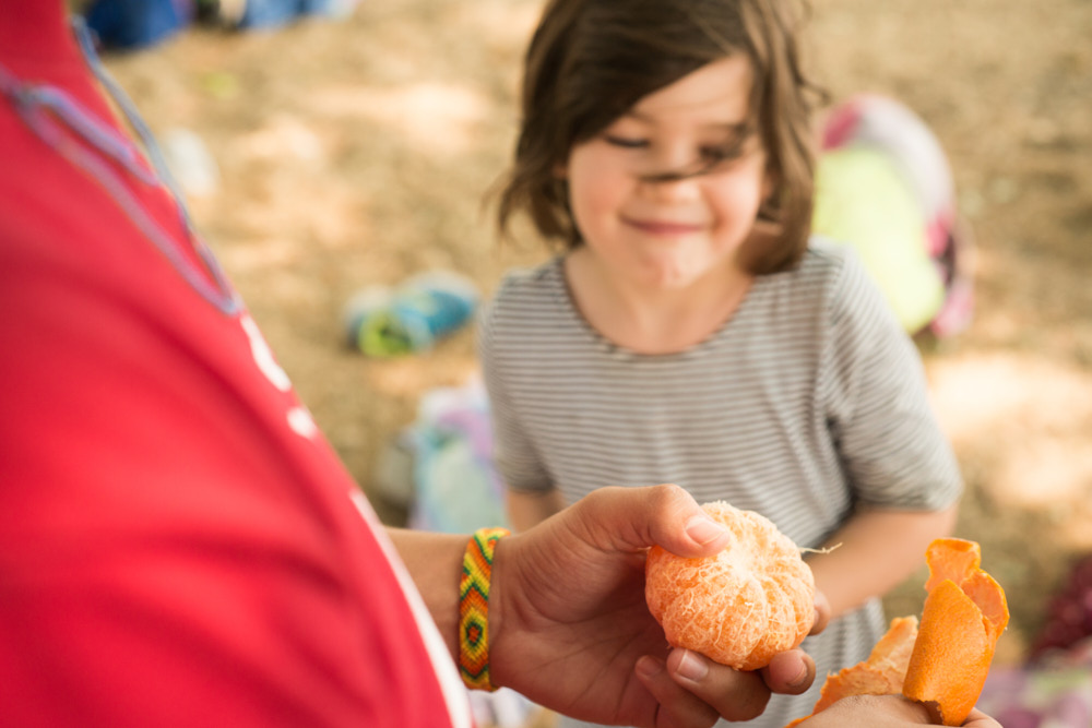 A girl looks at an orange peeled by her counselor