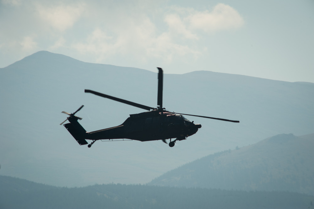 A helicopter flying with mountains in the background