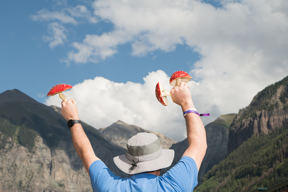 A man with a hat holding mushrooms in the air