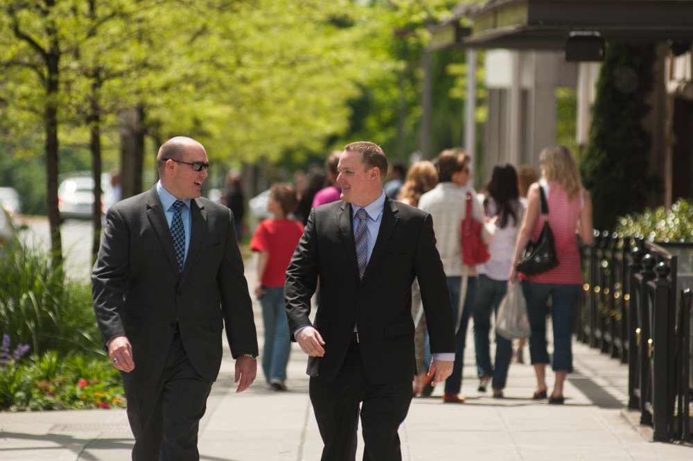Two men in suits walk and talk outside
