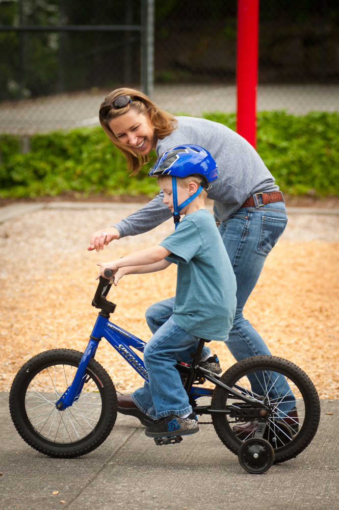 A woman helping her son ride a bicycle