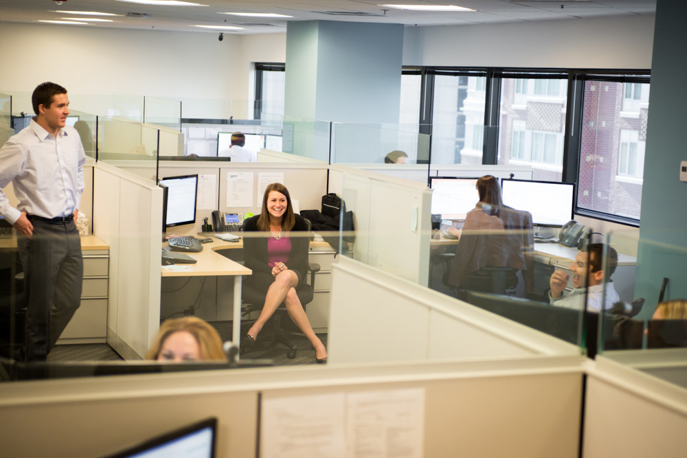 Office workers laughing and talking in their cubicles