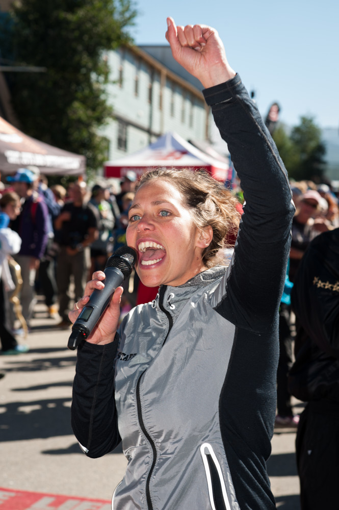 A female announcer shouts into a microphone while cheering