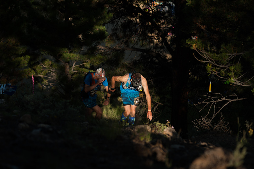 A runner climbing a hill in a patch of sunlight