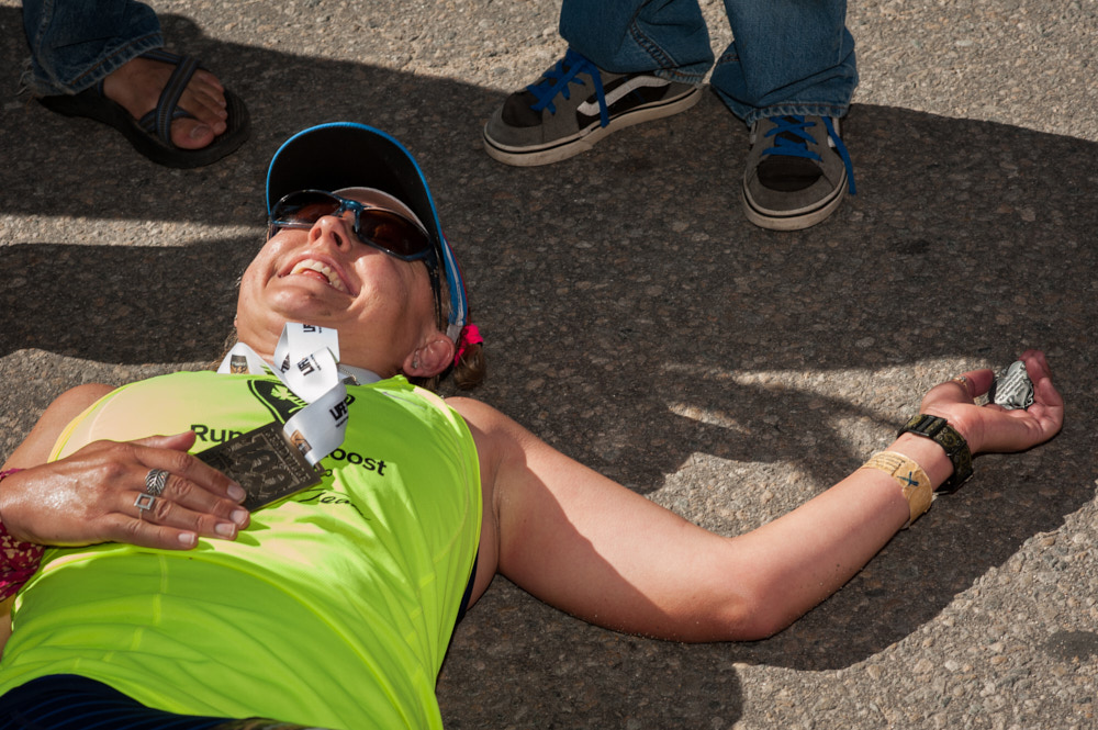 A smiling runner collapsed on the ground after finishing