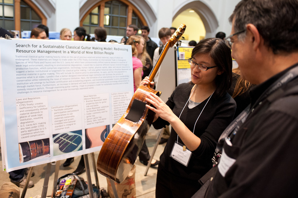A student makes a poster presentation while holding a guitar