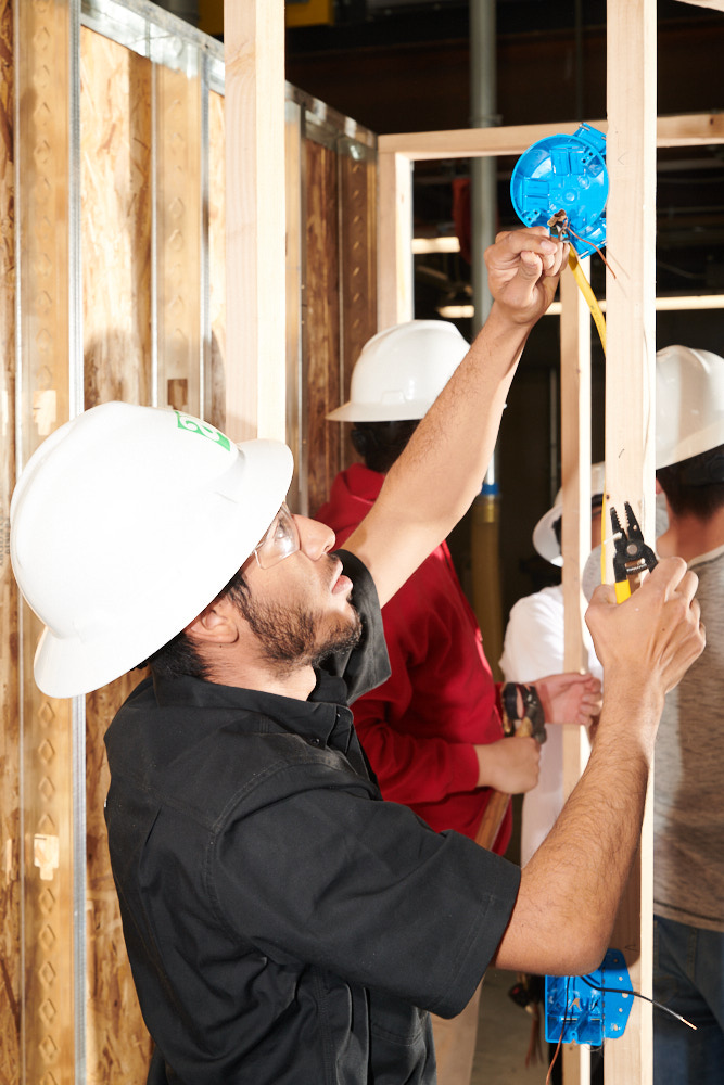 A student wearing a hard hat practicing electrical work