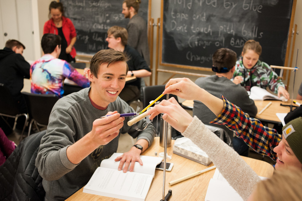 Three students work on a science experiment in a classroom