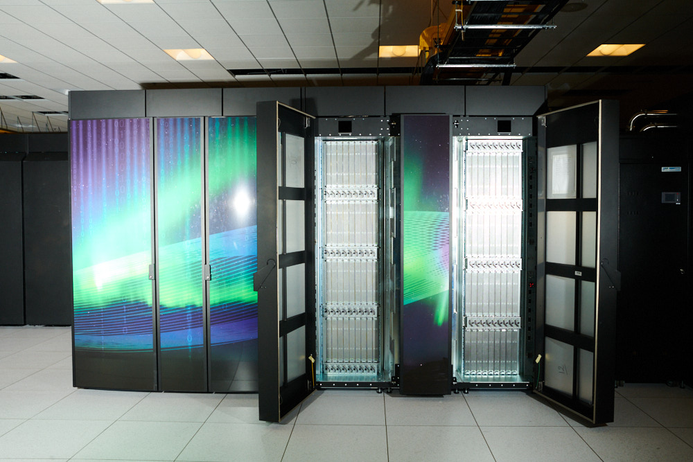 Open cabinets show racks of nodes in the Cheyenne supercomputer