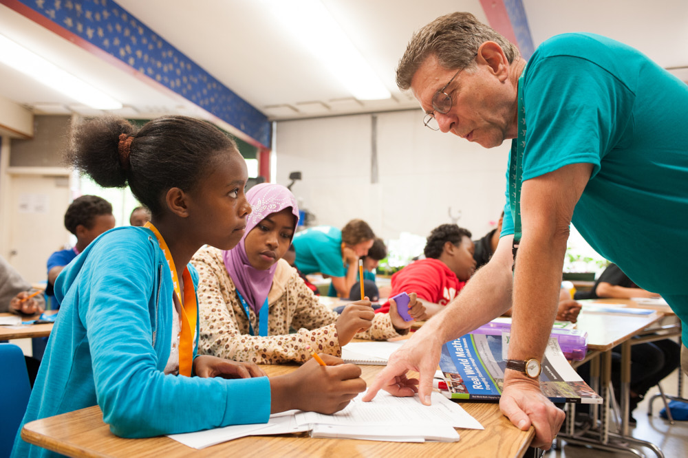 A teacher talking to high school students at their desk