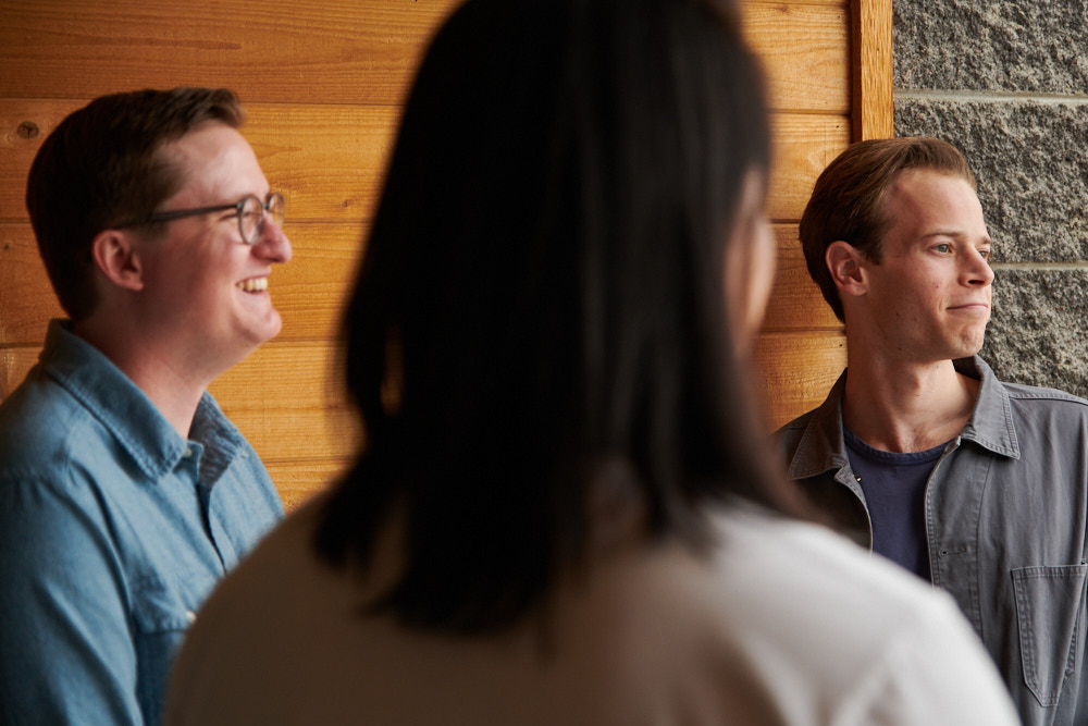 Three employees smiling during a conversation