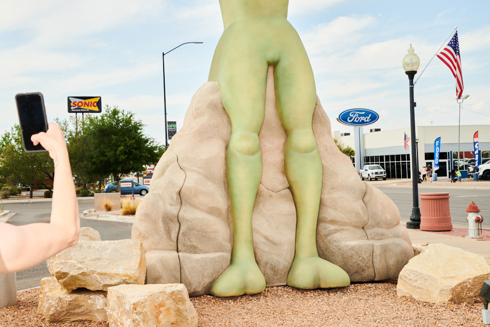 A person taking a picture of an alien torso statue