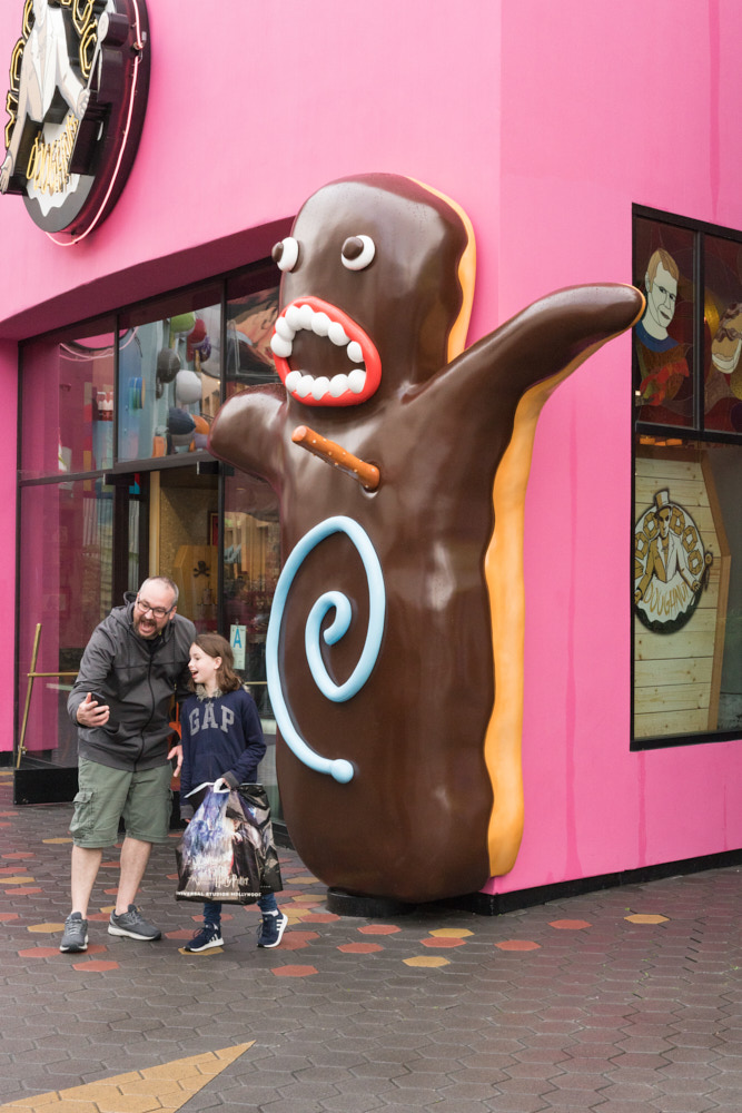 Two people taking a selfie in front of a huge donut monster statue