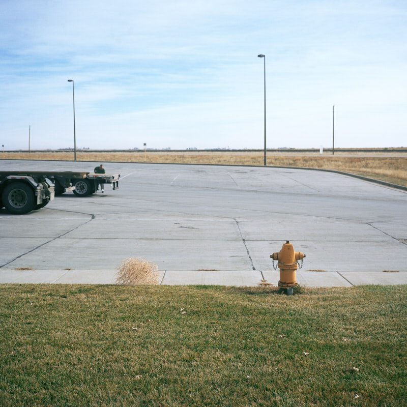 A tumbleweed at a truck stop with a fire hydrant