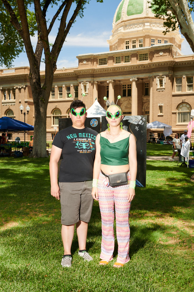 Two people posing for a portrait in downtown Roswell wearing alien glasses