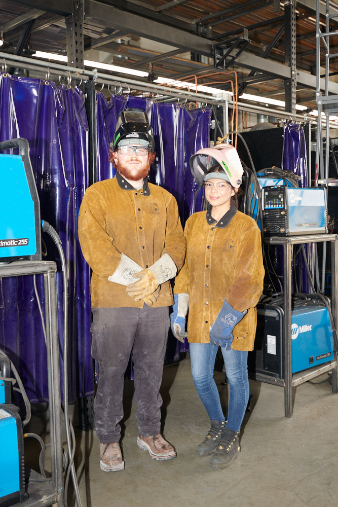 Welding students wearing safety equipment pose for a portrait