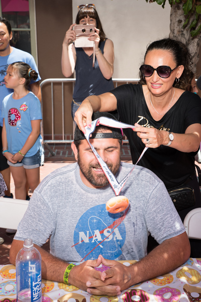 A woman presents a man with a medal shaped like a donut