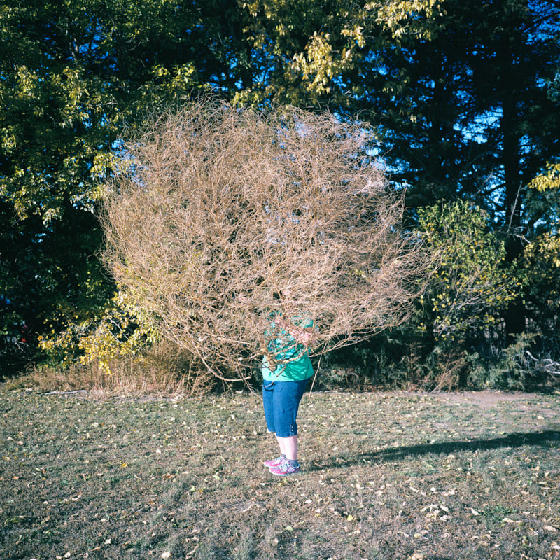 A woman holding a huge tumbleweed