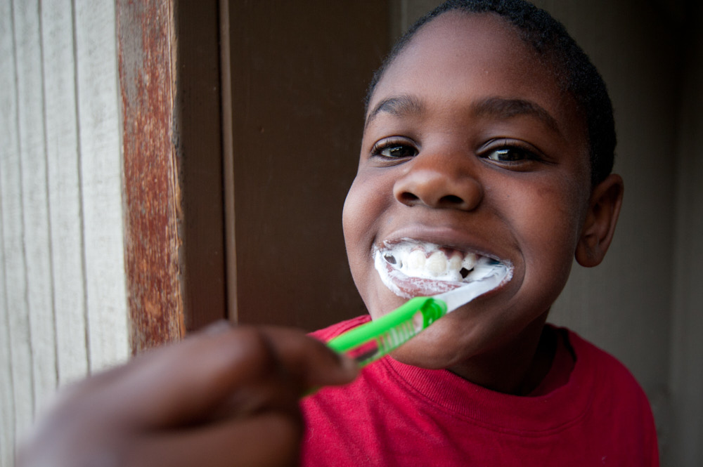 A boy smiles while brushing his teeth