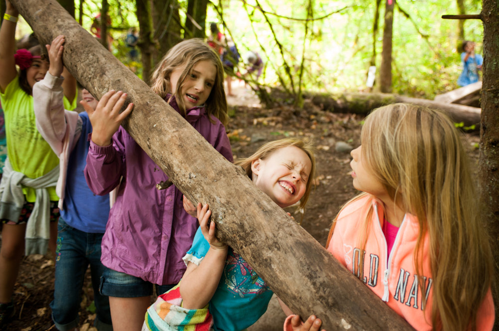 A group of young girls lifts a large log