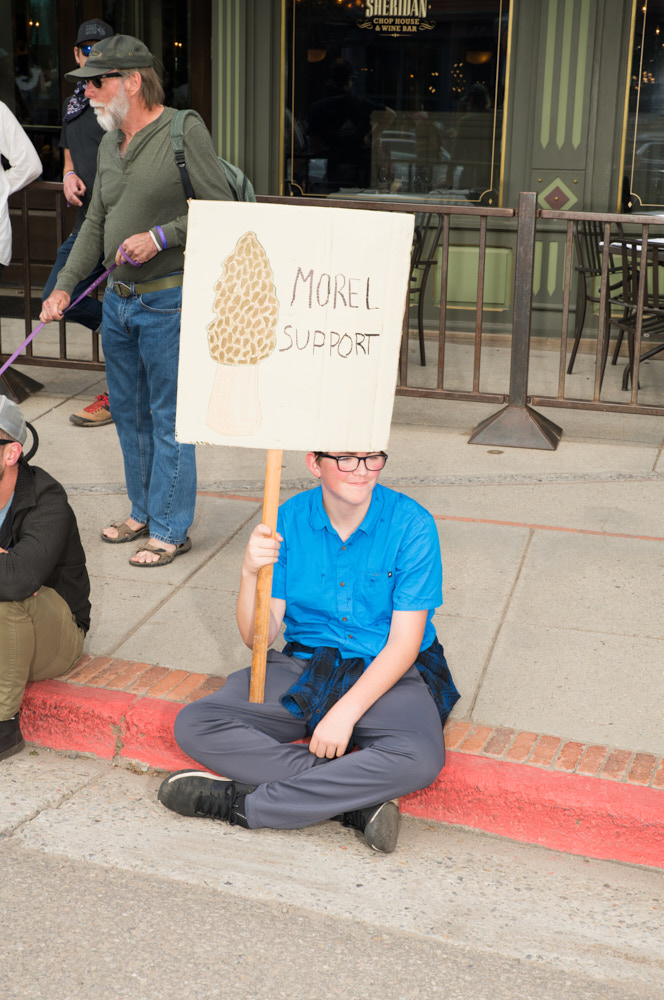 A boy holding a punny mushroom sign