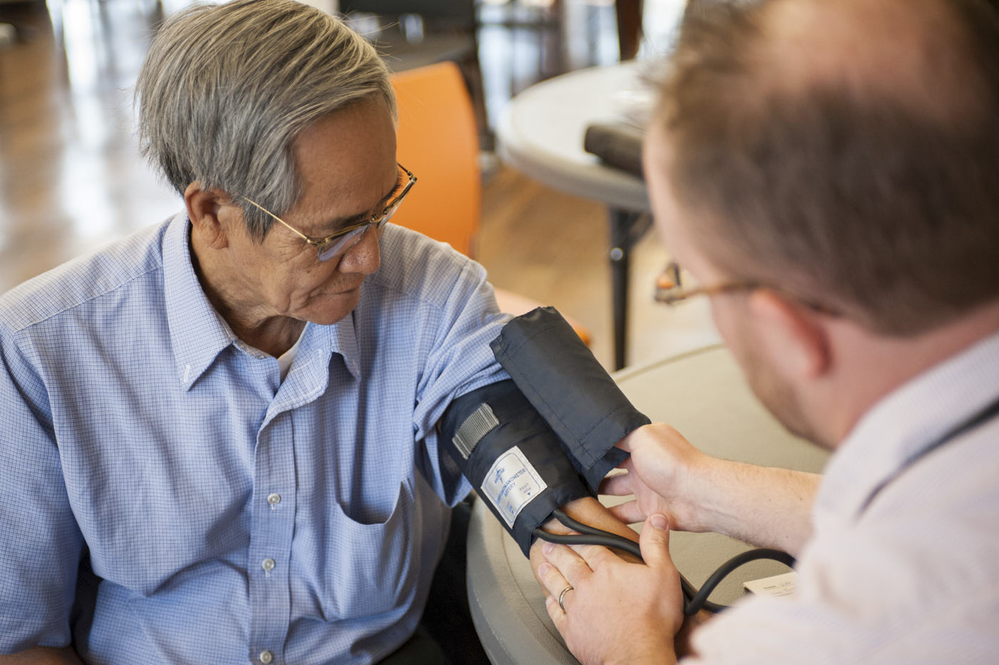 A man receiving a medical checkup from a doctor with a blood pressure cuff.